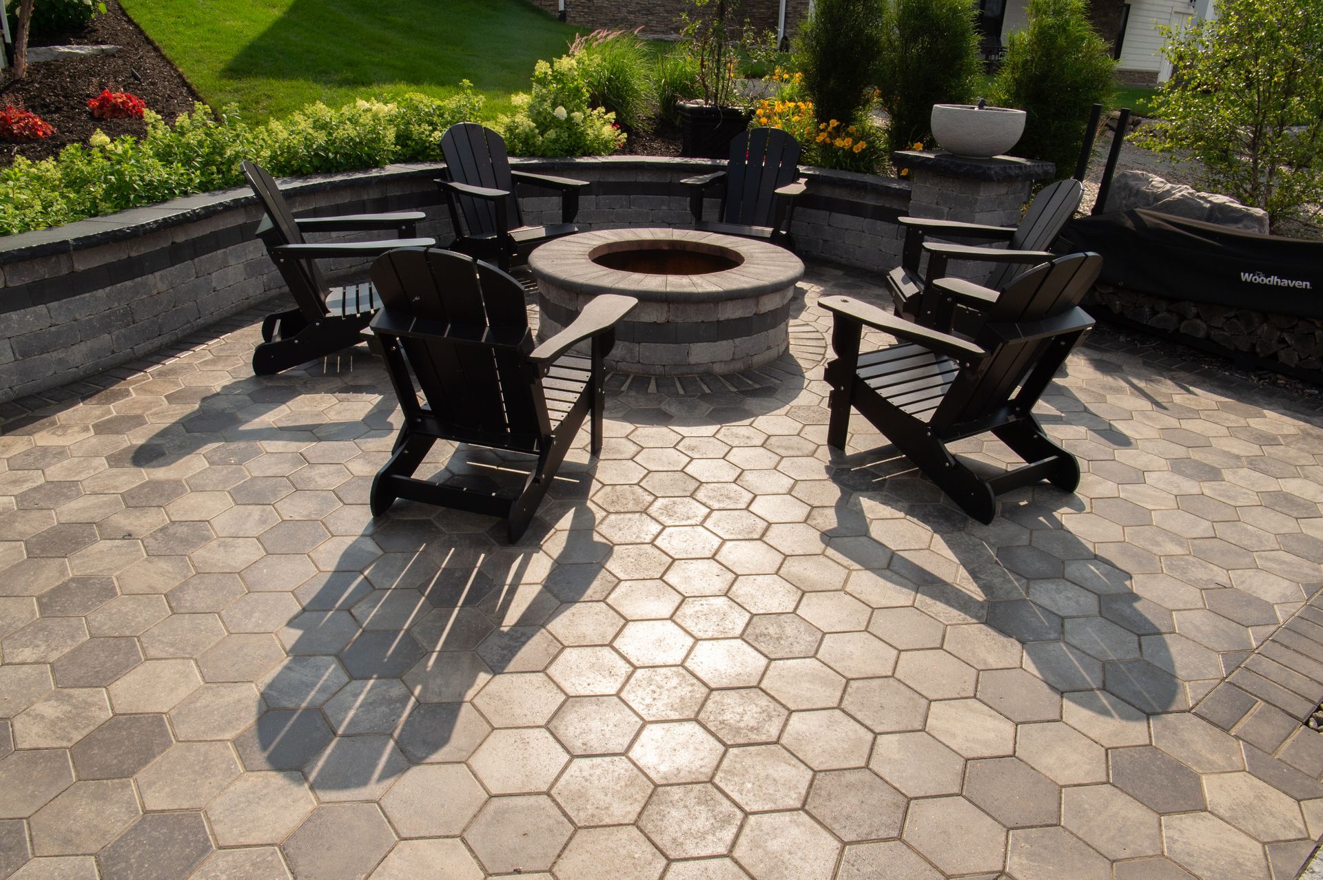 Patio with fire pit surrounded by Adirondack chairs; hexagonal pavers.