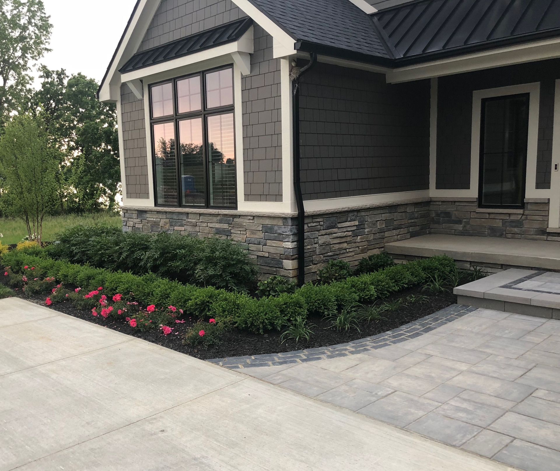 Exterior of a house with gray siding, stone accents, and a landscaped garden.