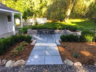 Outdoor patio with stone path, table, and landscaping.