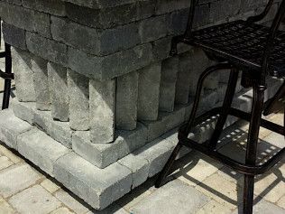 Stone patio bar with dark metal stool.