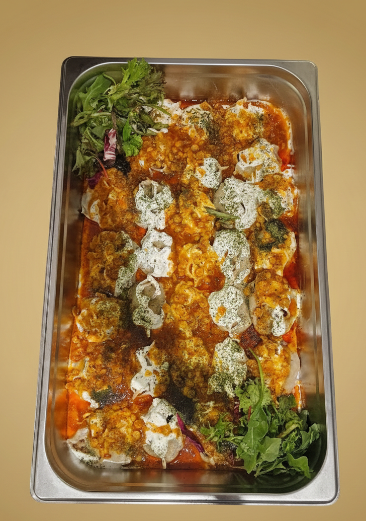 Bricka med mat, troligen en gryta, med sås, krämiga toppings och örter.