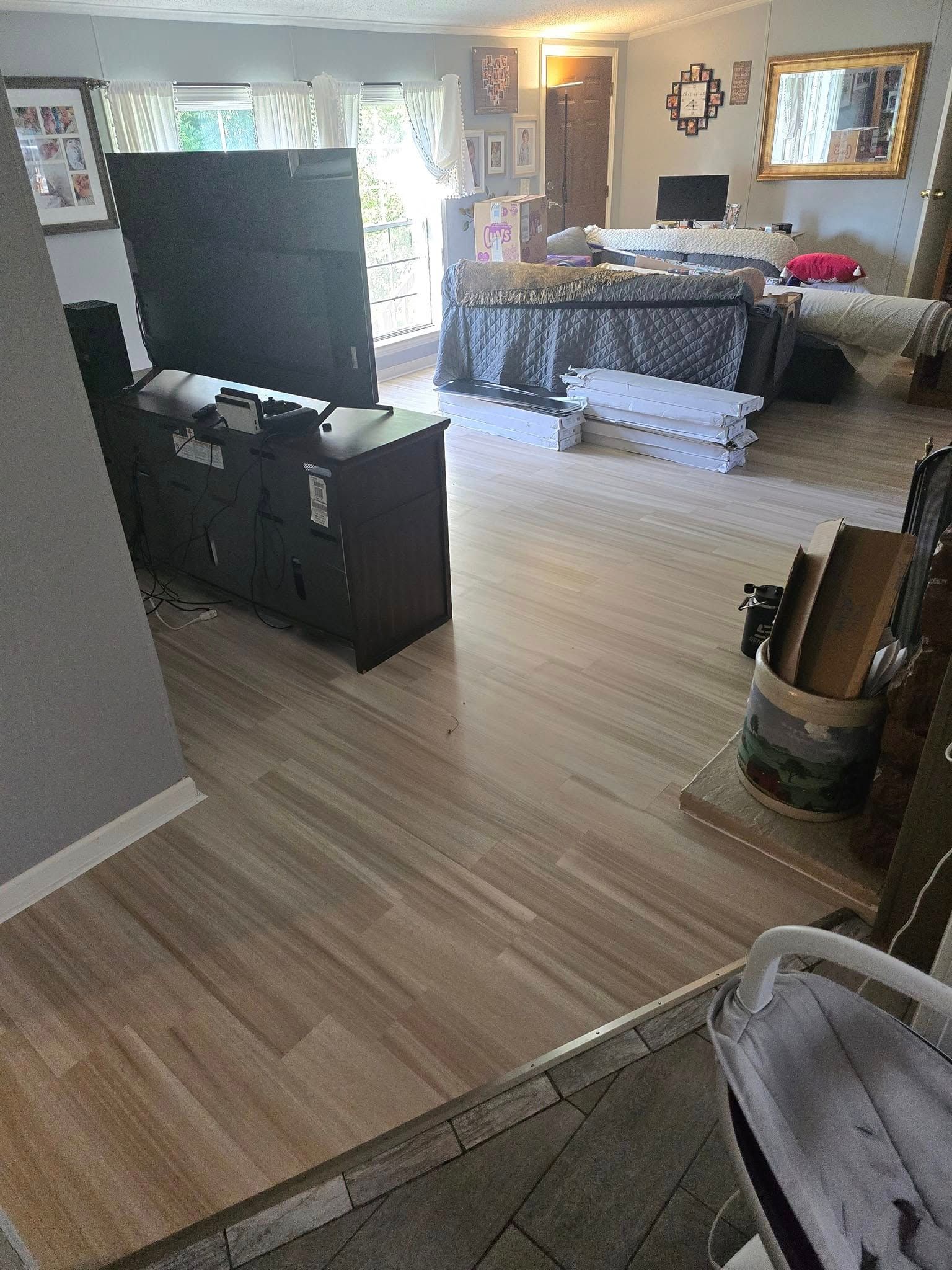 Bright living room with a TV, dark cabinet, couch, chair, and wooden flooring.