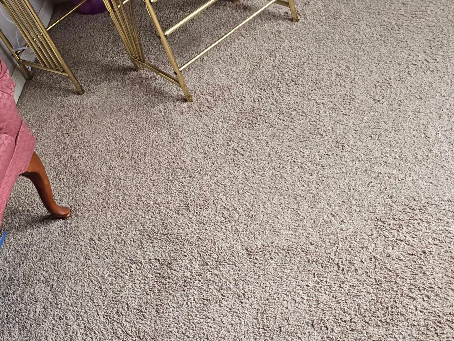 Speckled beige carpet with chair legs and a pink upholstered seat at the edge