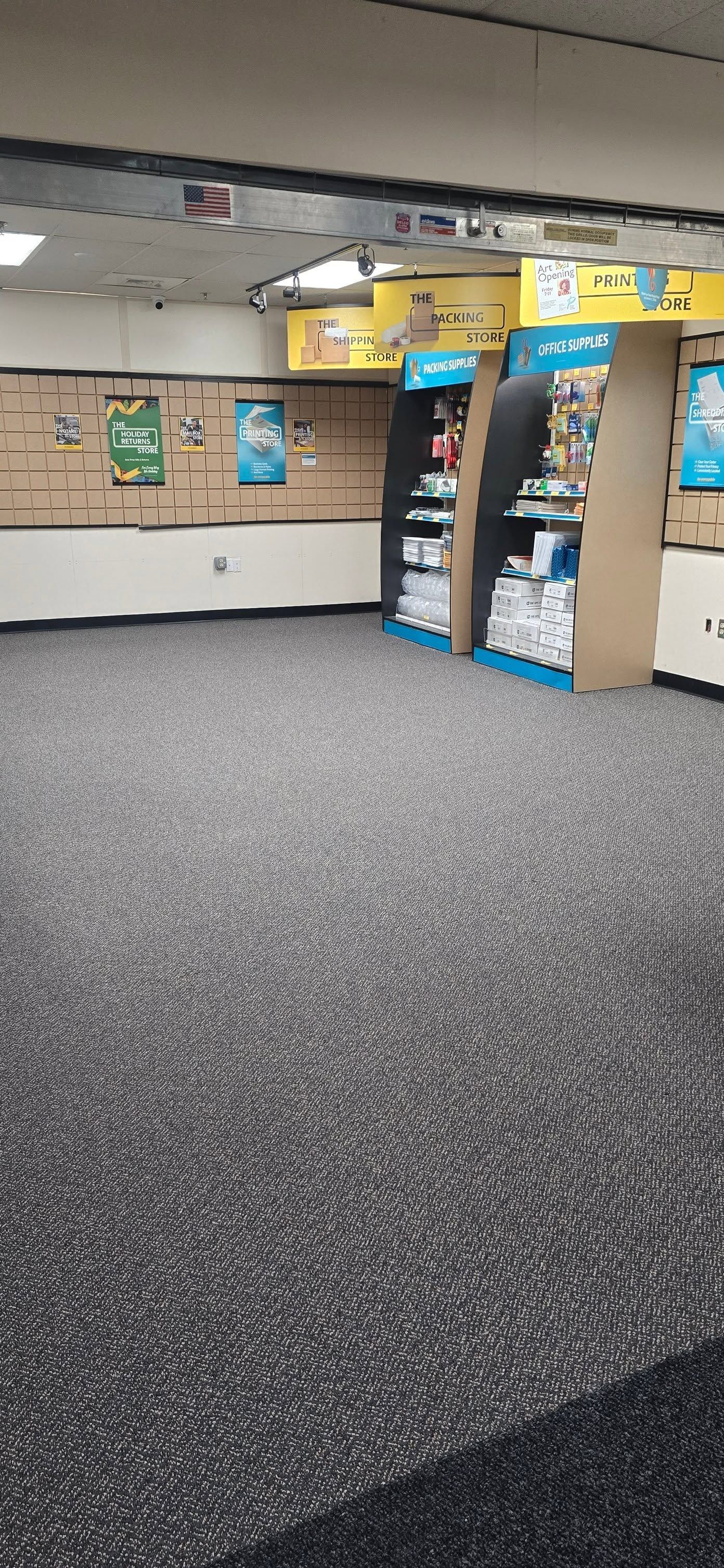 Empty office lobby with patterned carpet, bulletin boards, and an open blue-framed doorway