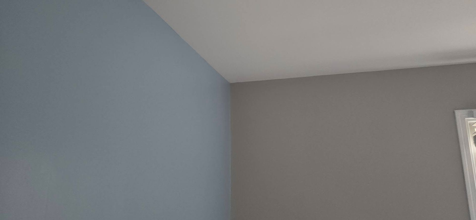 Blue and gray interior walls meeting at a corner near a window