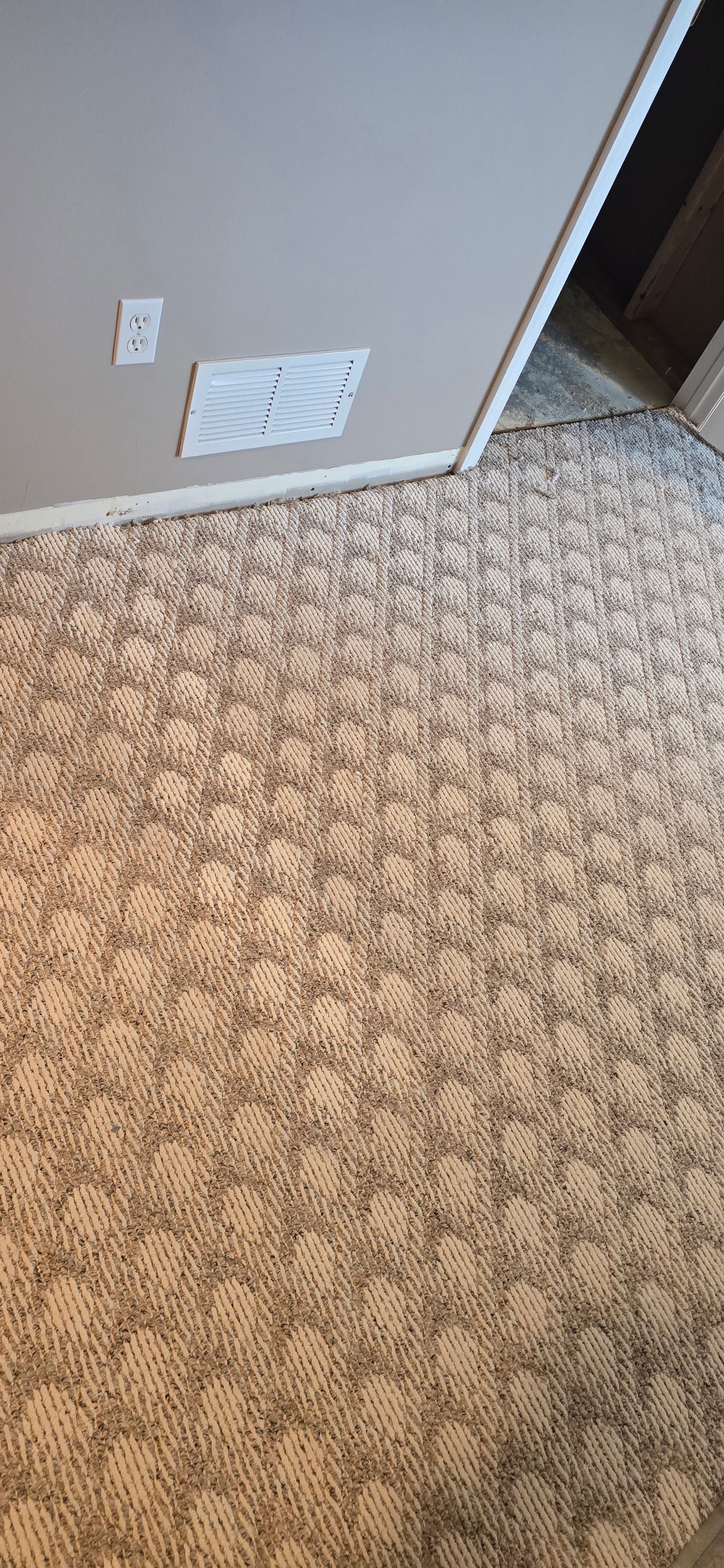 Carpeted room corner with beige walls, a white vent, and a doorway.