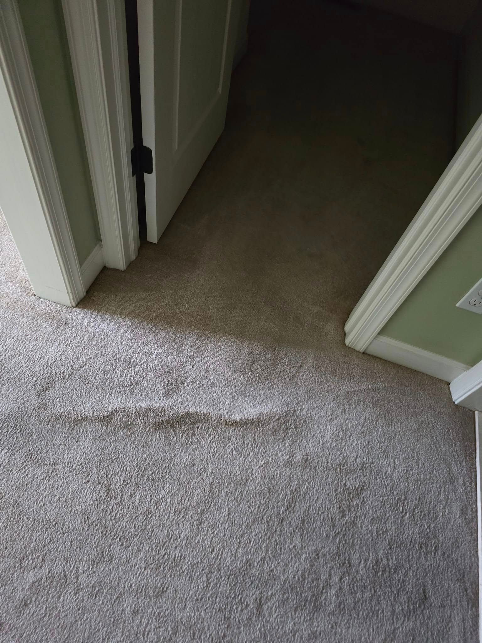 Carpeted hallway with a large light-colored stain near a doorway