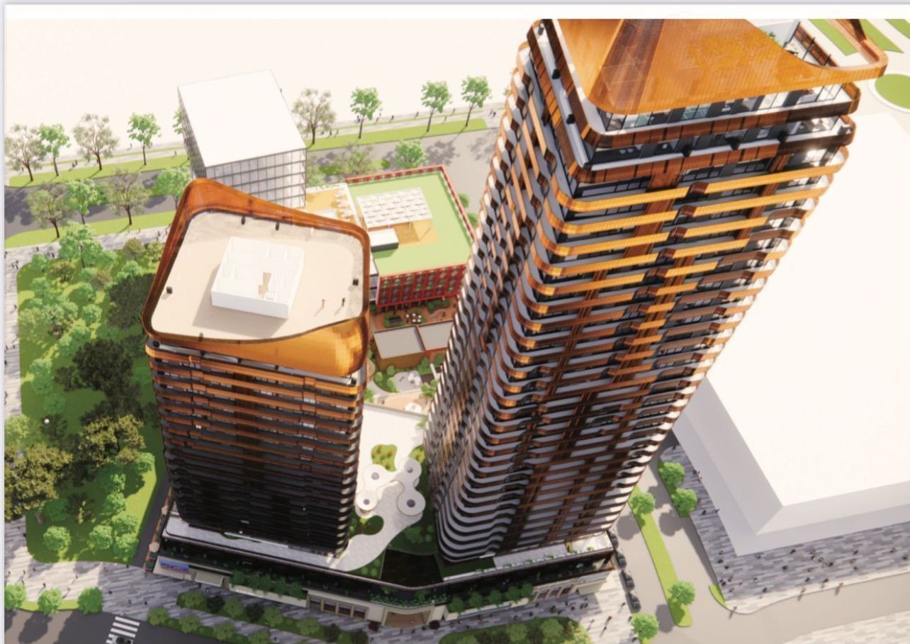 High-angle view of two modern, brown high-rise buildings with a courtyard and surrounding cityscape.