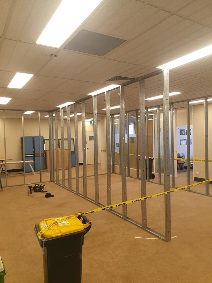 Empty Office Under Renovation With Exposed Wall Studs and Yellow Caution Tape — Damien Thompson Plastering King Creek, NSW