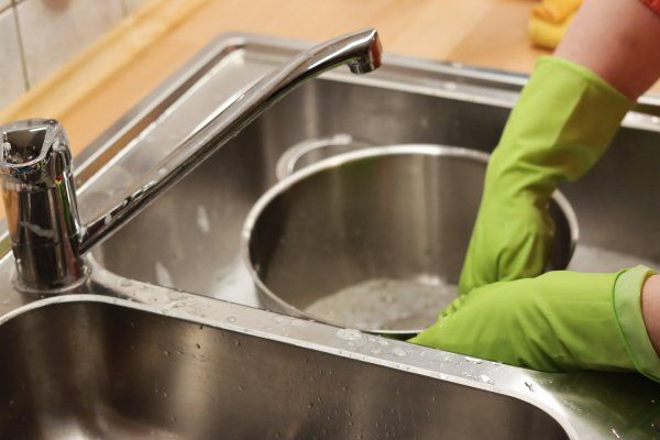 A person getting water from the kitchen faucet