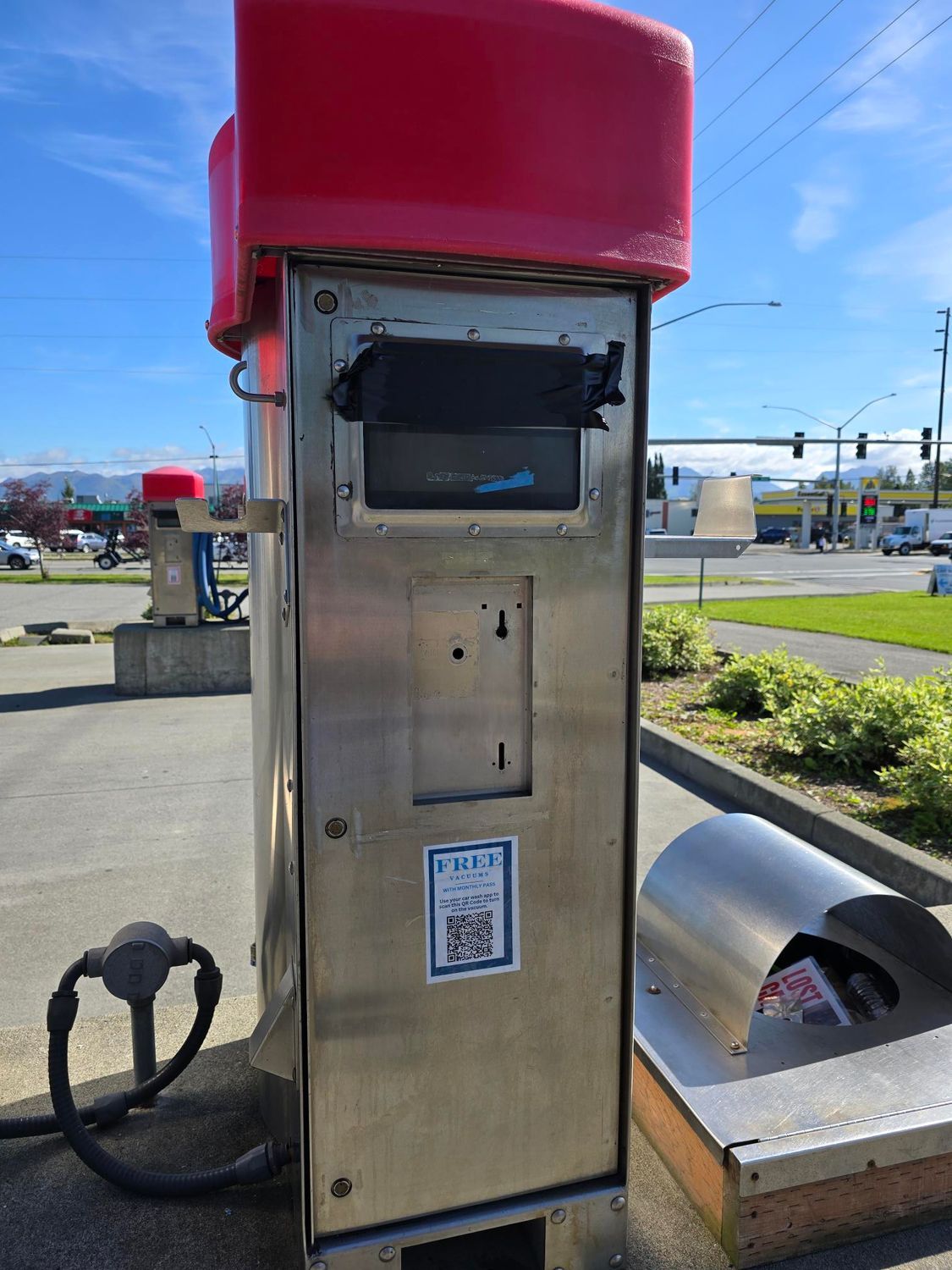 A vacuum with a red top is sitting on the side of the road.