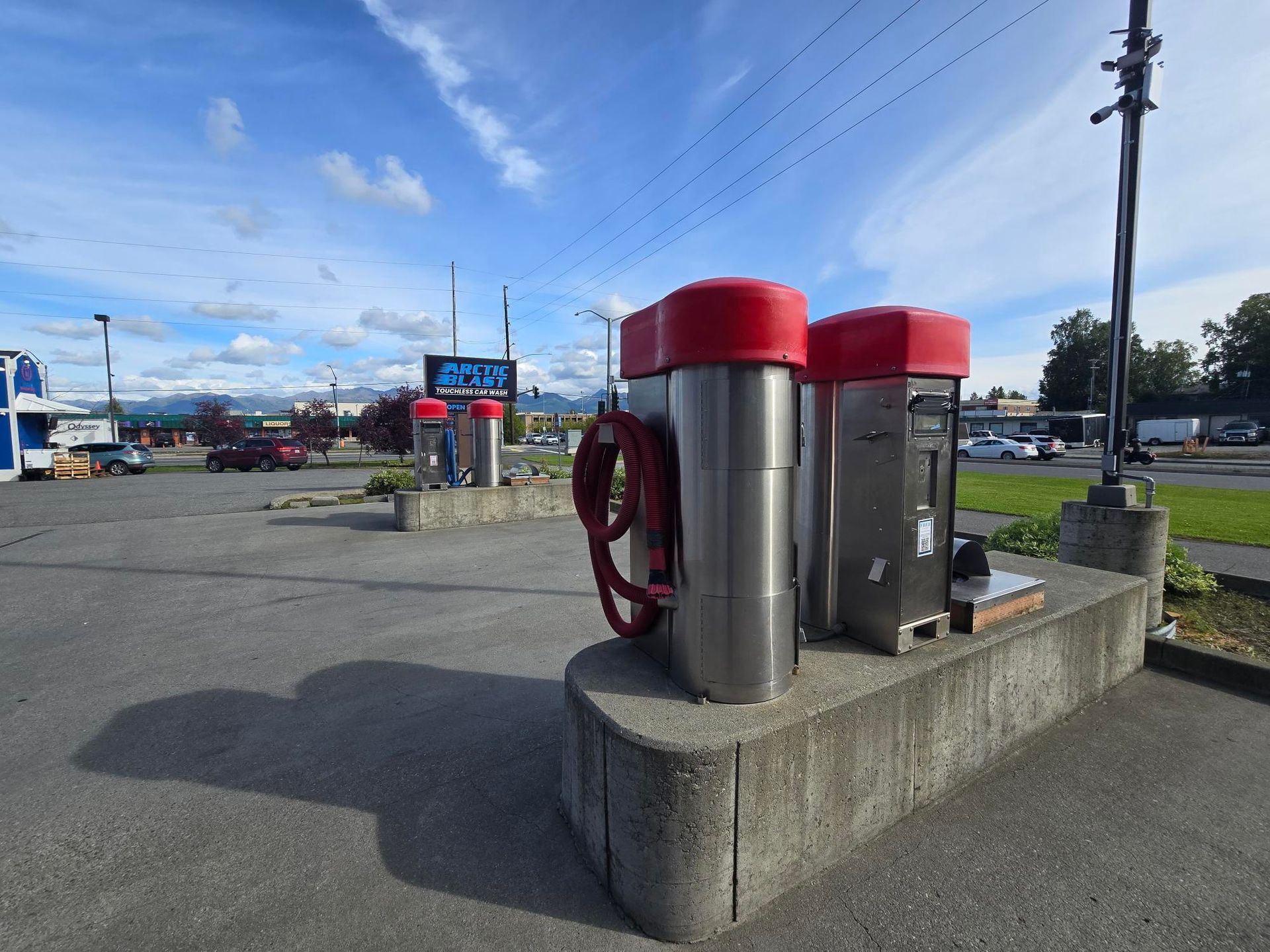 A vacuum station is sitting on the side of the road in a parking lot.