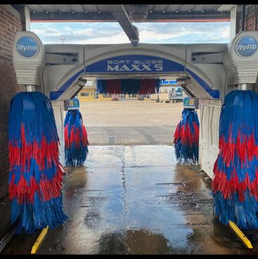 A car is being washed in a car wash with a blue light shining on it. Petit carwash 