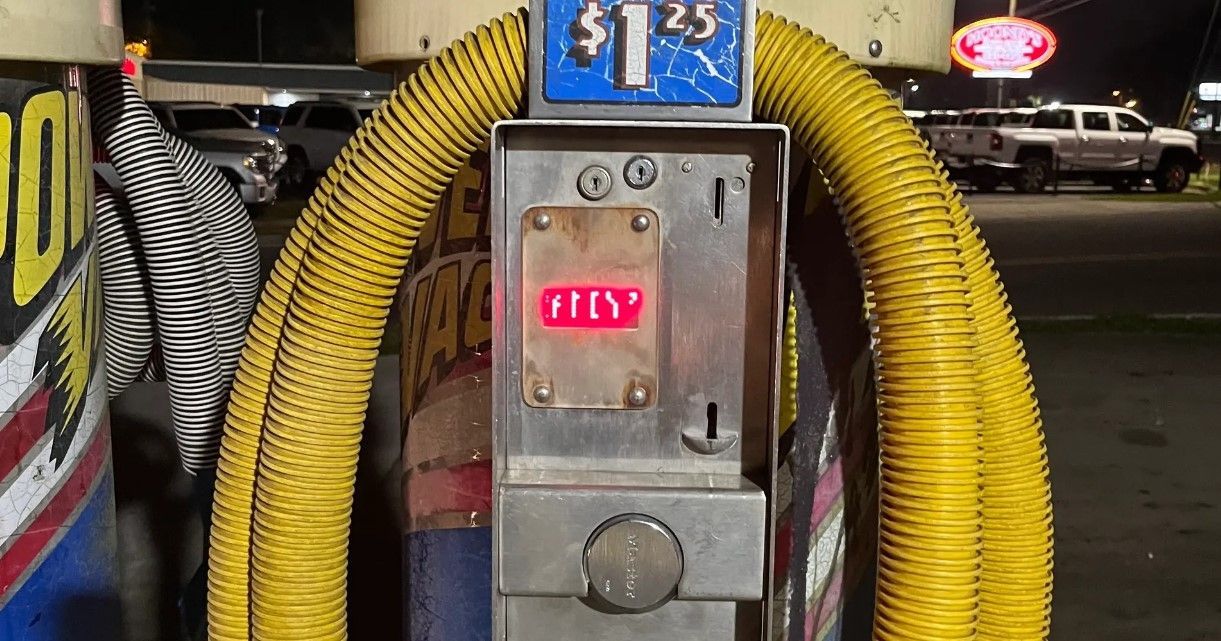 A coin operated car wash machine with a yellow hose attached to it.