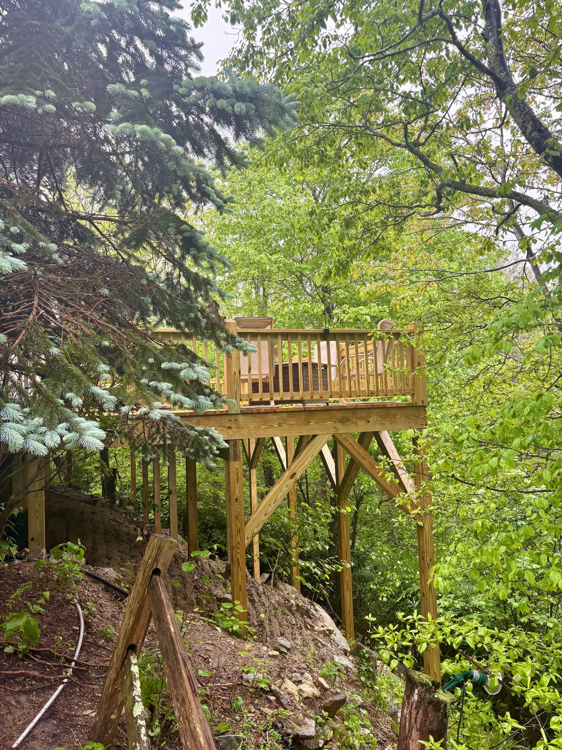 Wooden deck built into a hillside, surrounded by trees.