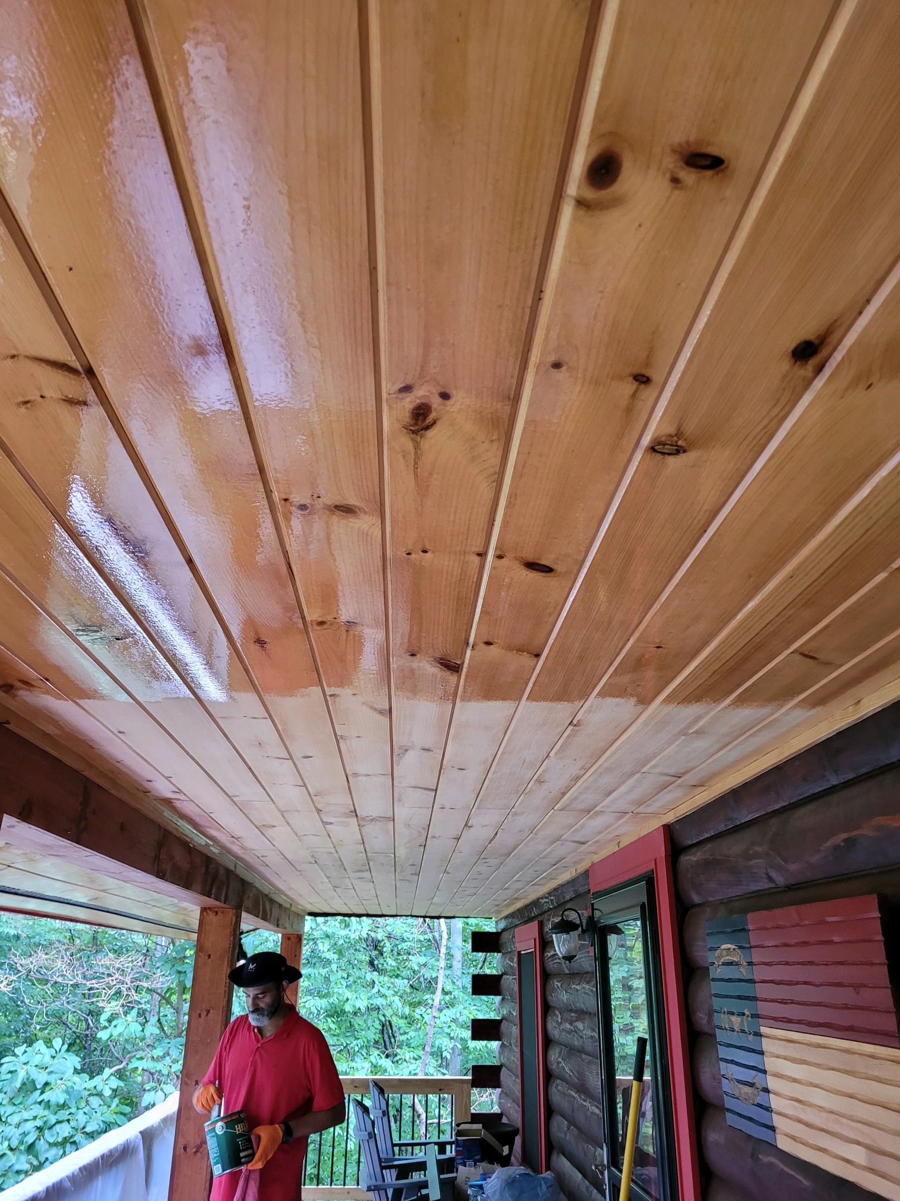 A man is standing on a porch with a wooden ceiling.