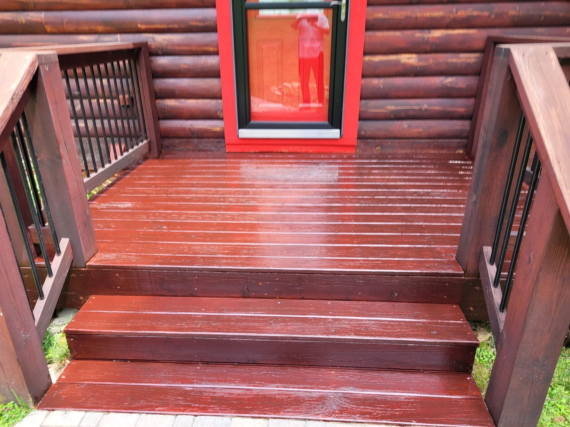 A wooden deck with stairs leading up to it and a red door.