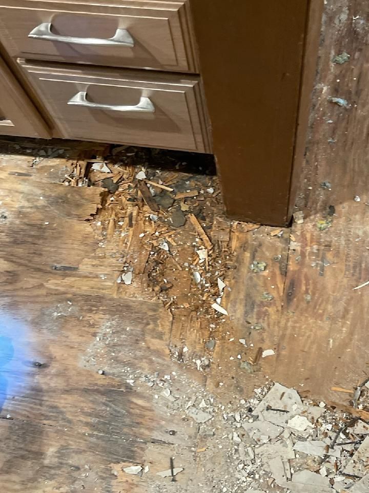 A kitchen floor with a lot of broken wood and concrete.