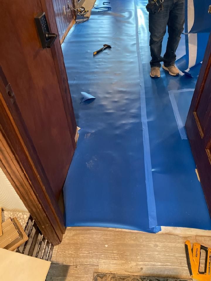 A man is standing on a blue tarp in a hallway.