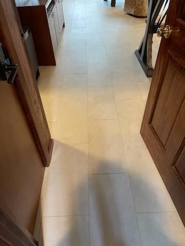 A hallway with white tile floors and a wooden door.