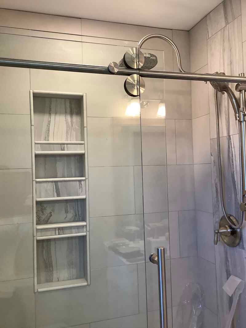 A bathroom with a sliding glass shower door and a shower head.
