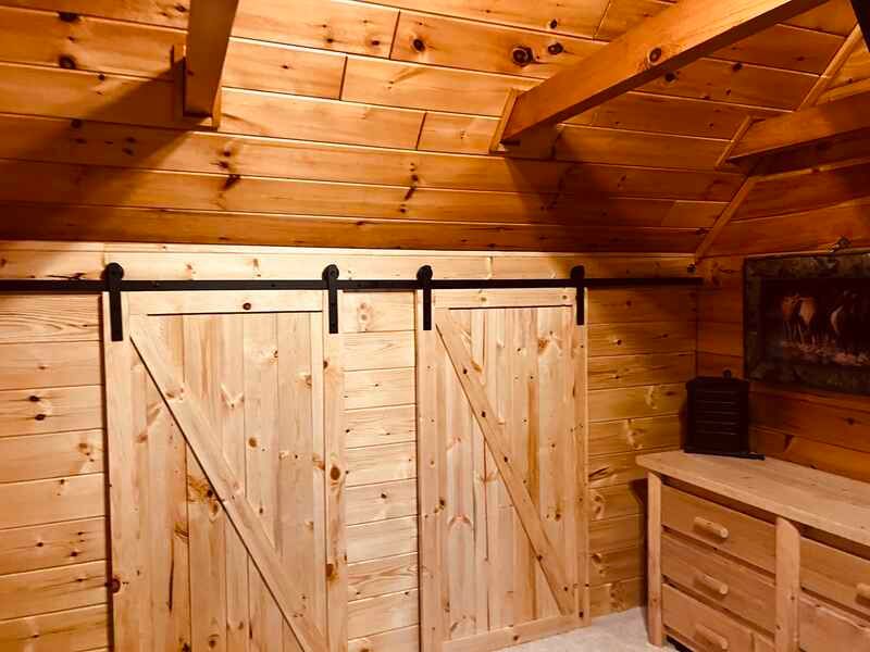 A wooden room with sliding barn doors and a dresser.