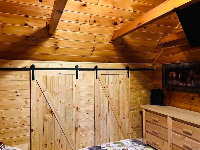 A bedroom in a log cabin with a sliding barn door.