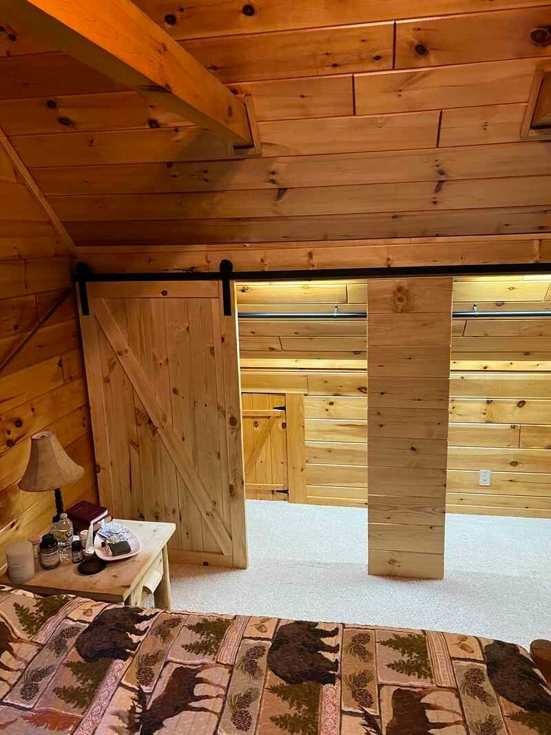 A bedroom in a log cabin with a sliding barn door.