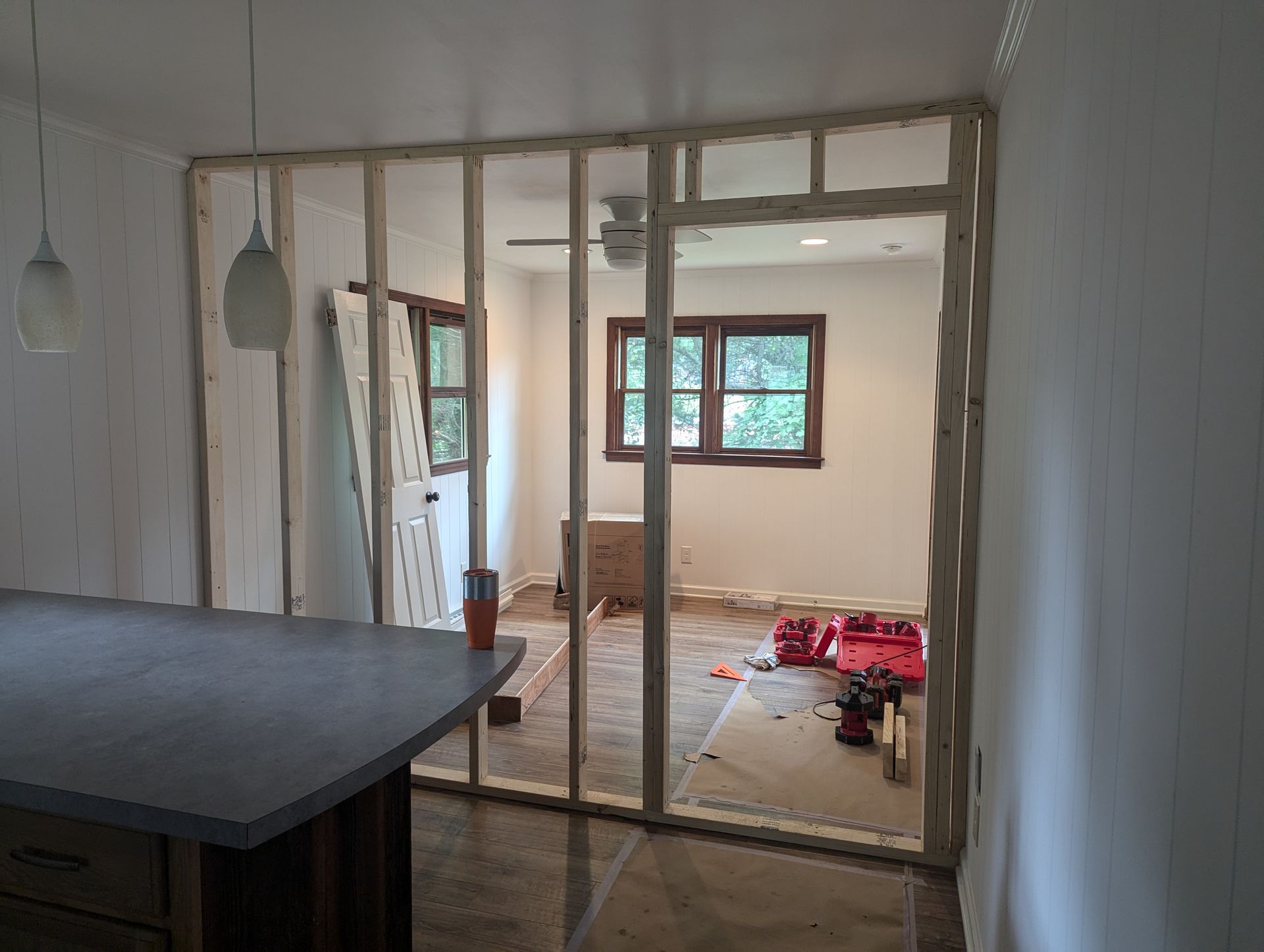 A room with a ceiling fan and a window is being remodeled.