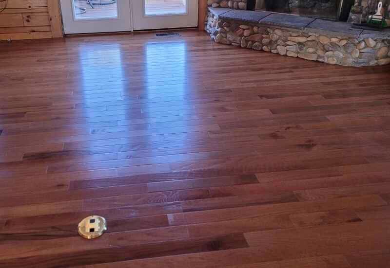 A wooden floor in a living room with a fireplace.