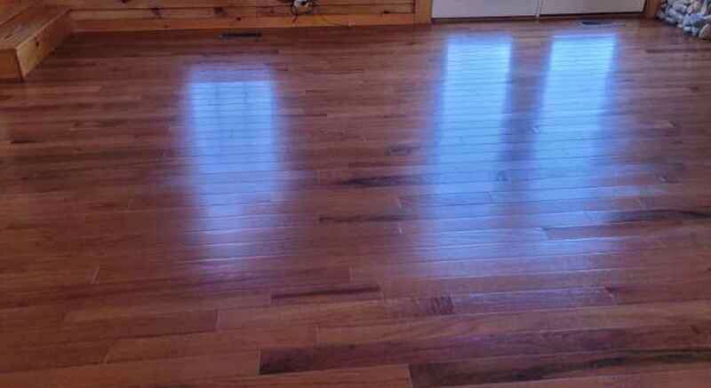A living room with hardwood floors and a reflection of the windows.