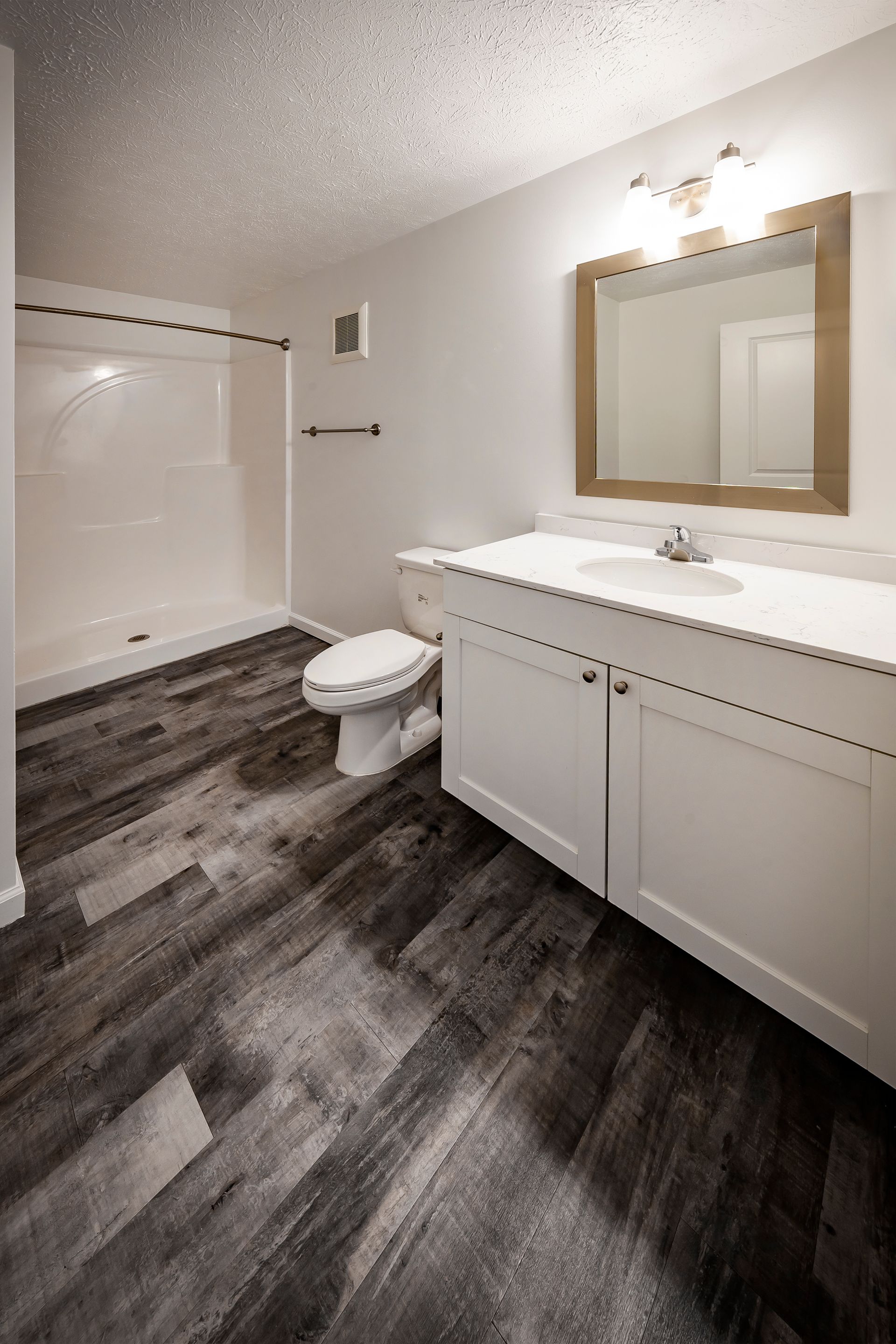 Empty bedroom with gray flooring, white walls, two closed doors, and a ceiling fan.