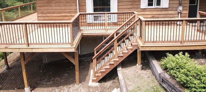 A wooden deck with stairs leading up to it and a house in the background.