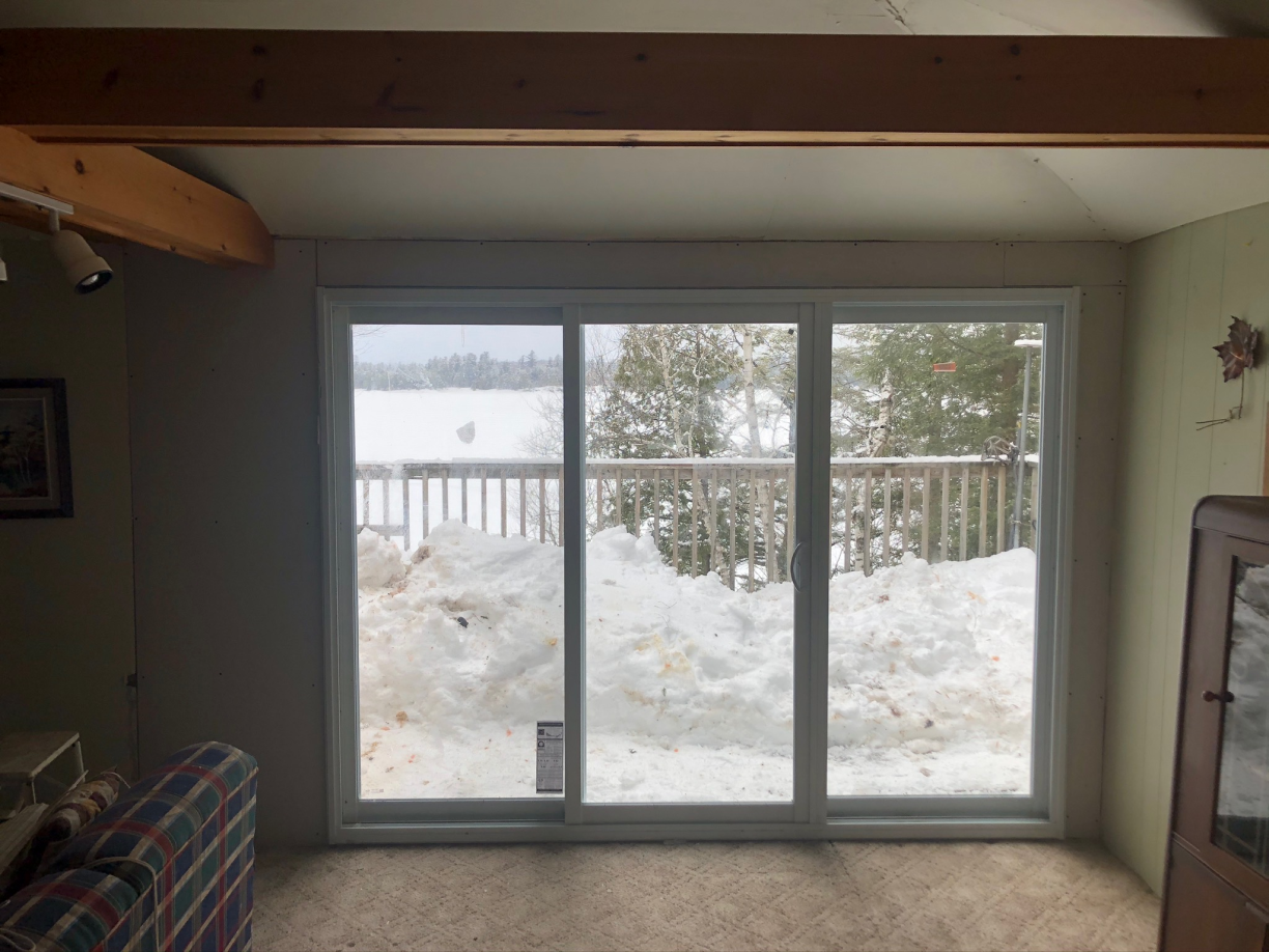 A living room with a sliding glass door leading to a snowy deck.