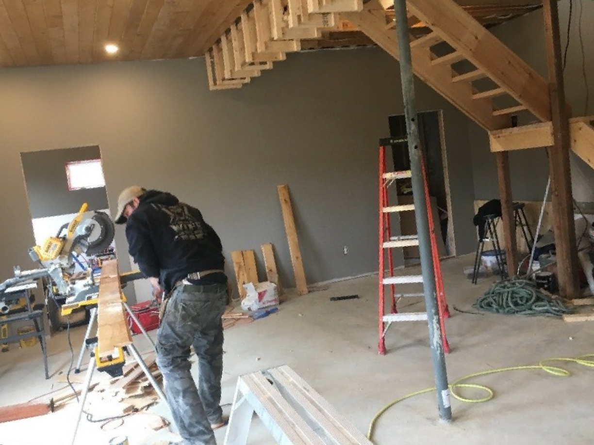 A man is working on a wooden staircase in a room.