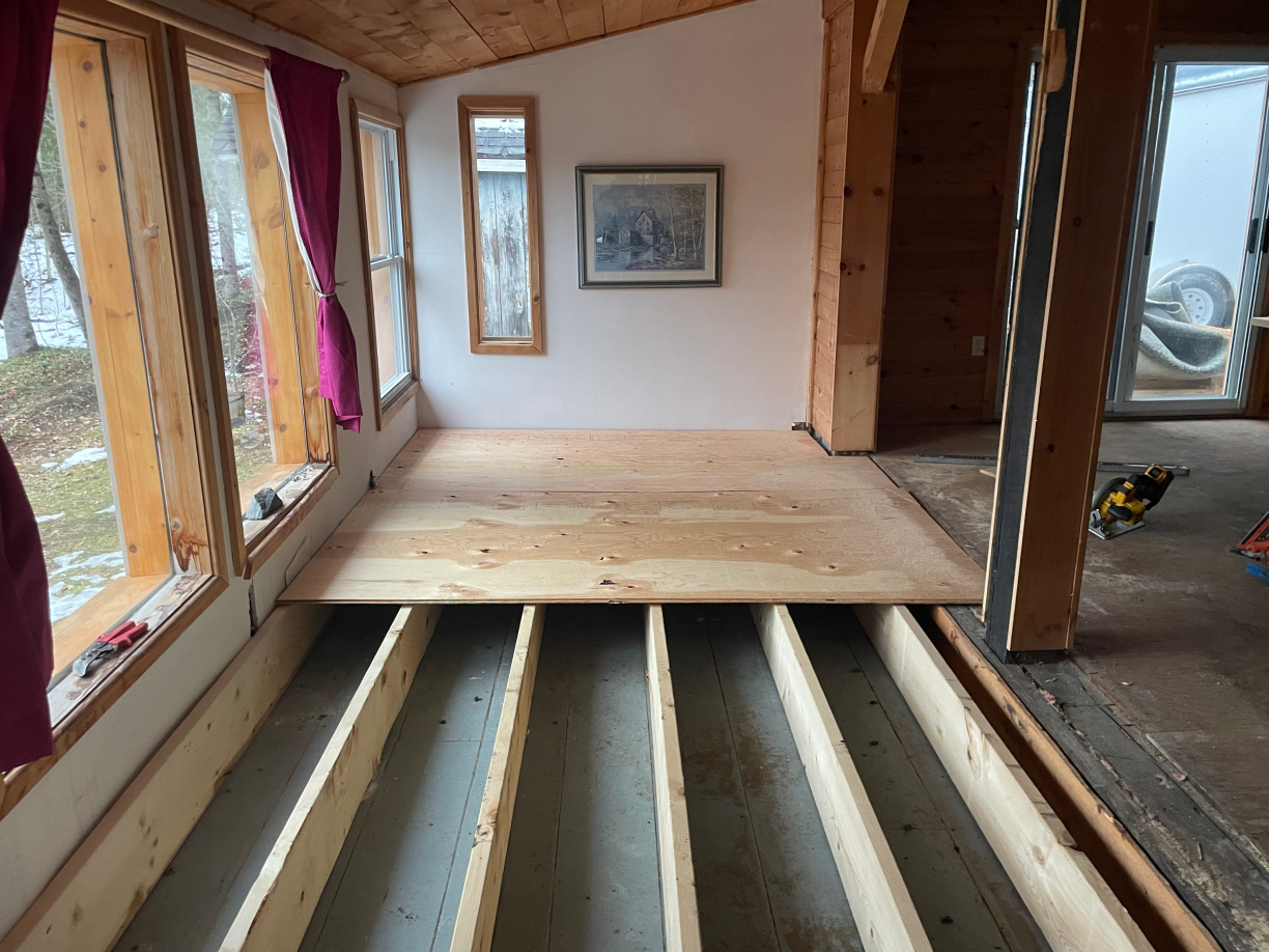 A room with a wooden floor and a picture on the wall