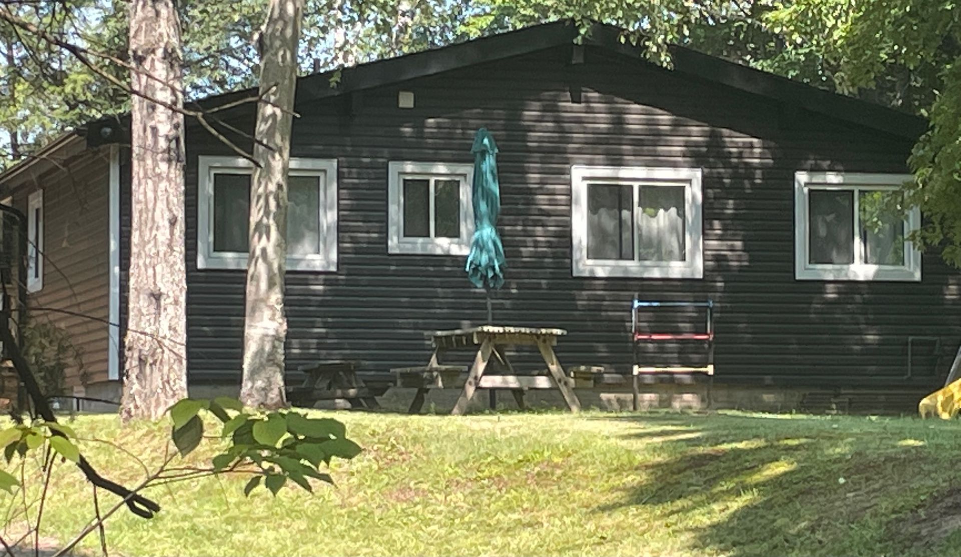A black house with a picnic table and umbrella in front of it.
