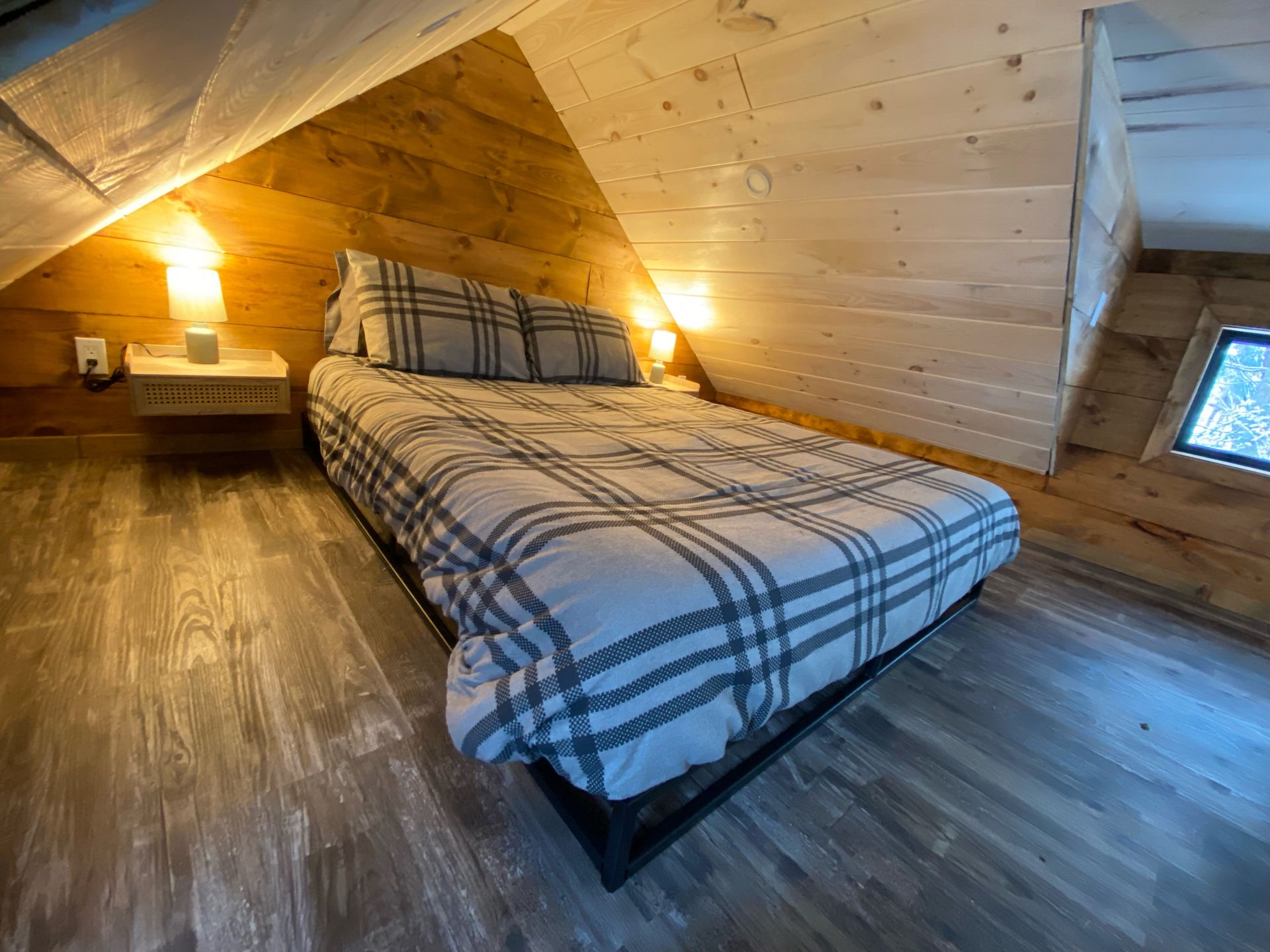 There is a bed in the attic of a cabin.