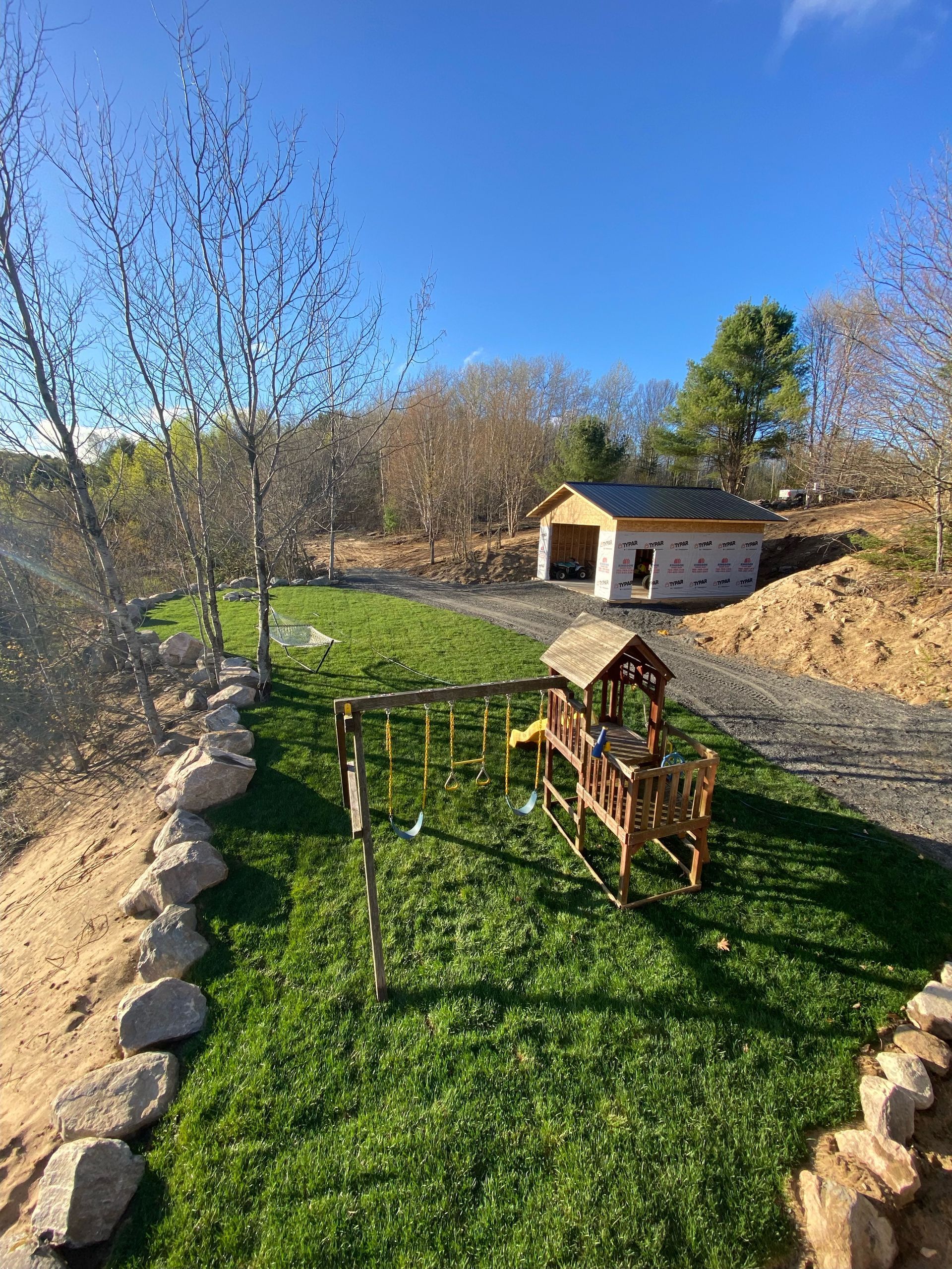 A wooden playground is sitting in the middle of a lush green field.