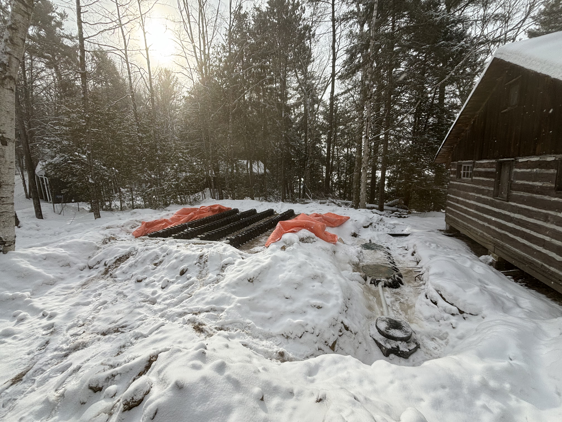 A snowy yard with a log cabin in the background.