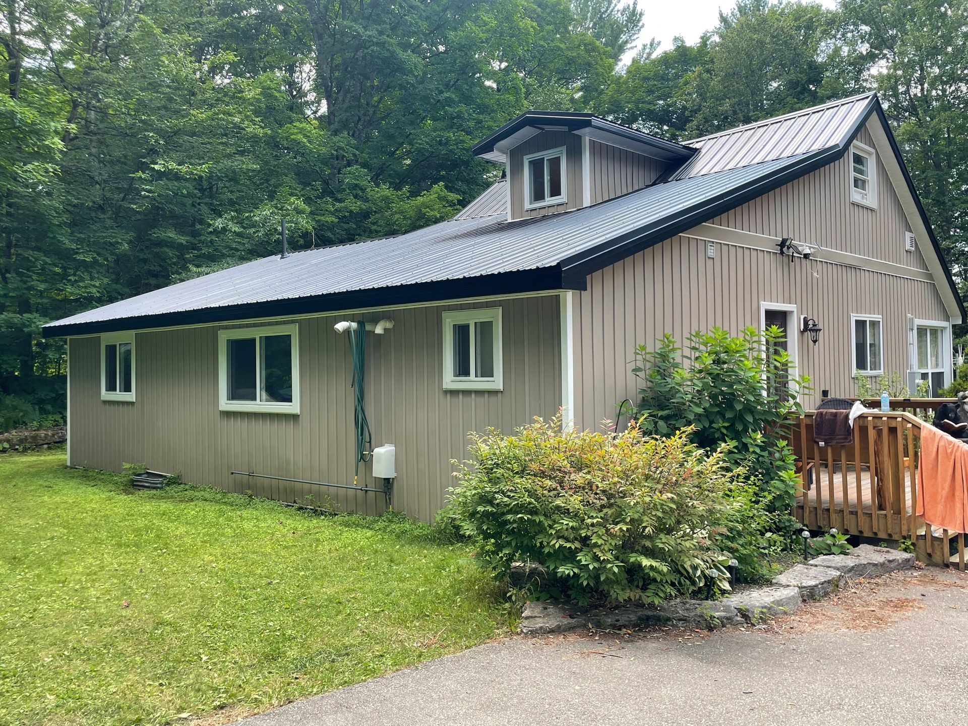 A house with a metal roof is surrounded by trees and grass.