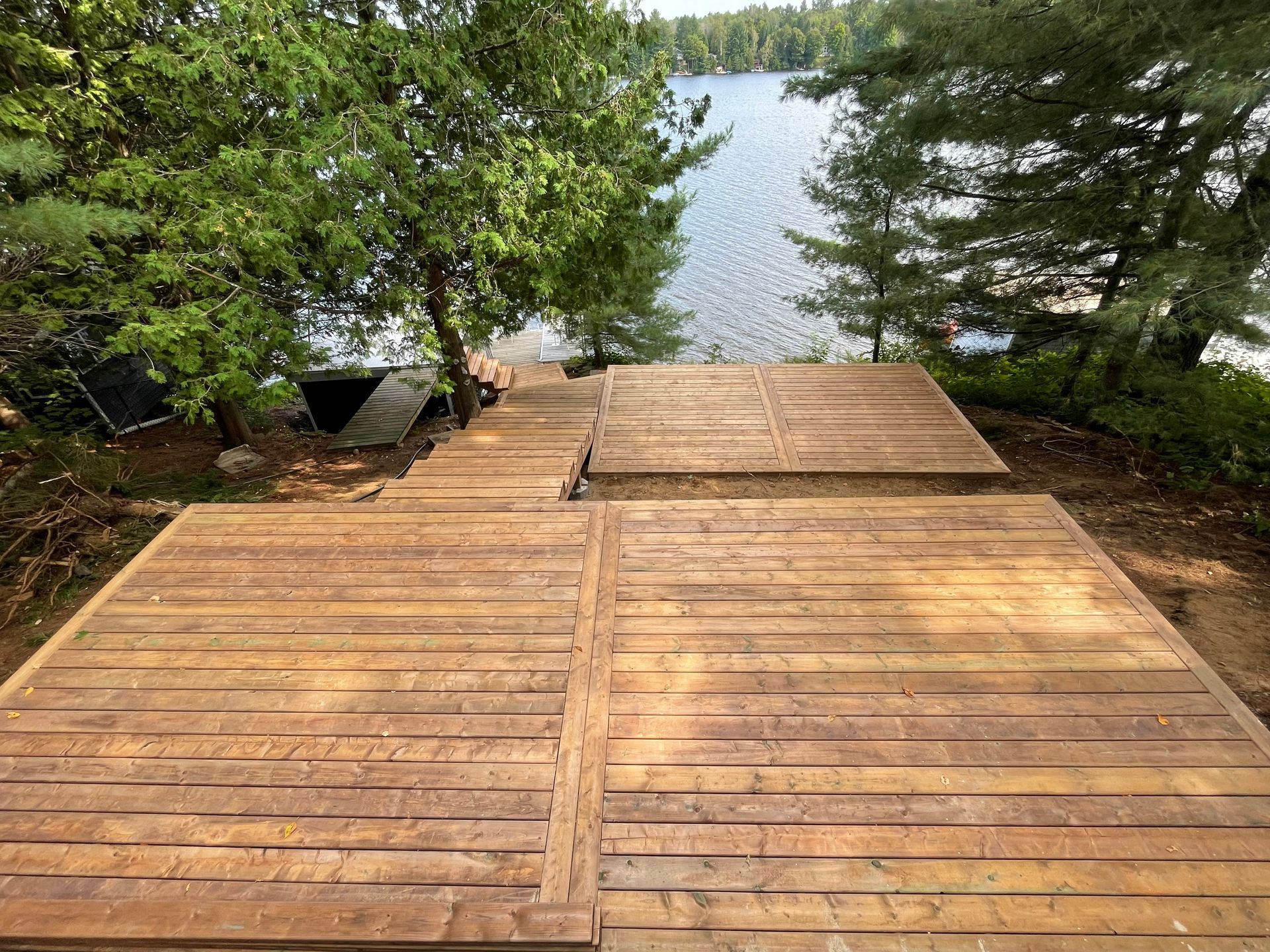 A wooden deck overlooking a lake with trees in the background.
