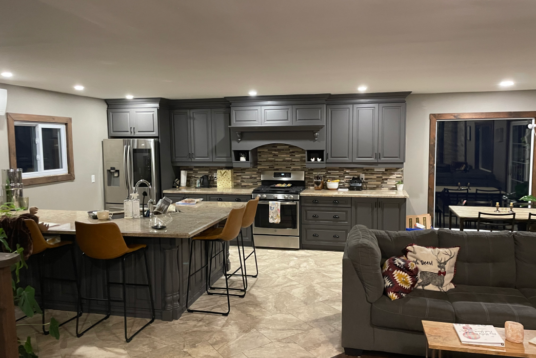 A living room with a couch and a kitchen with stainless steel appliances.