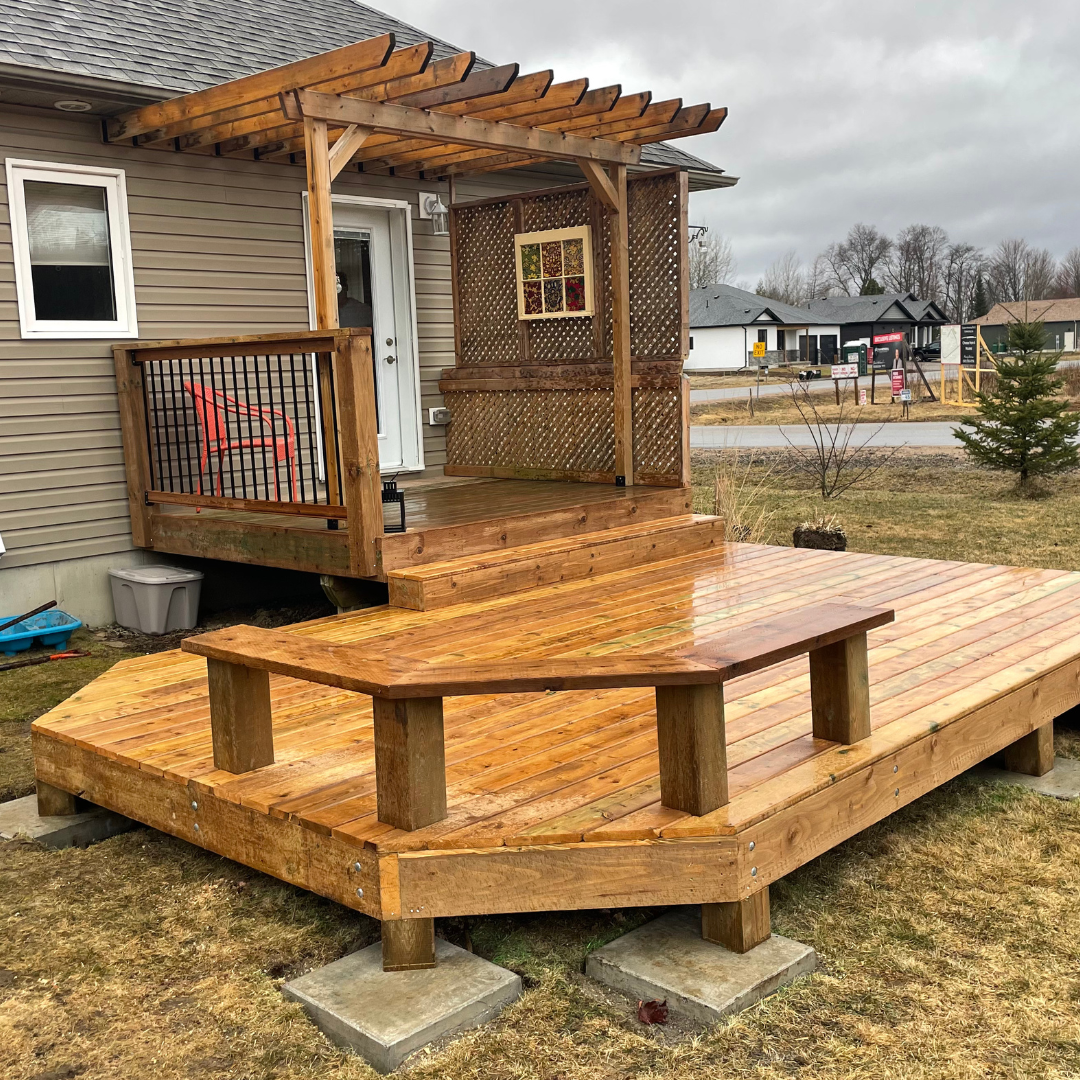 A wooden deck with a bench and a pergola in front of a house.