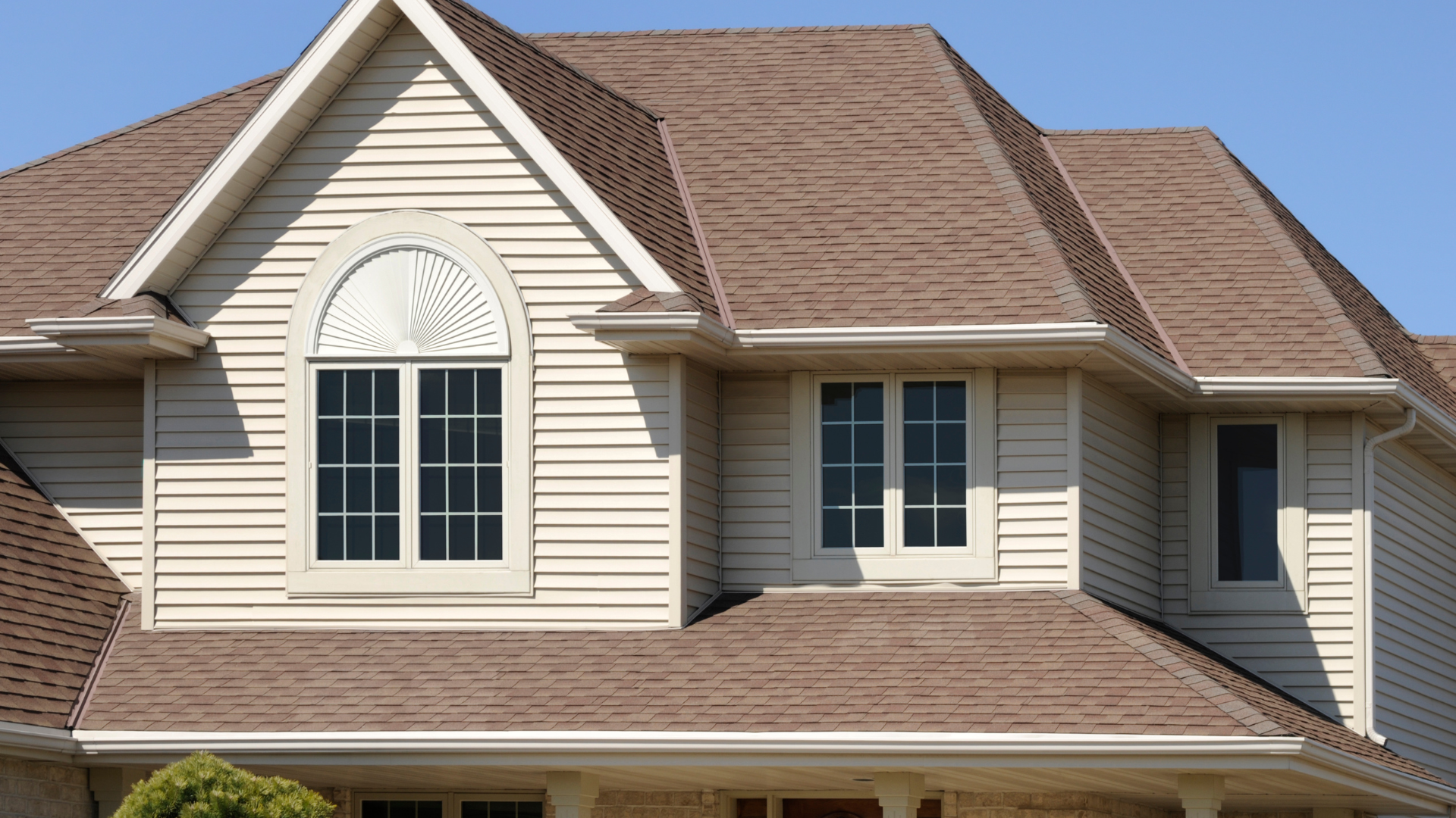A large house with a brown roof and white siding