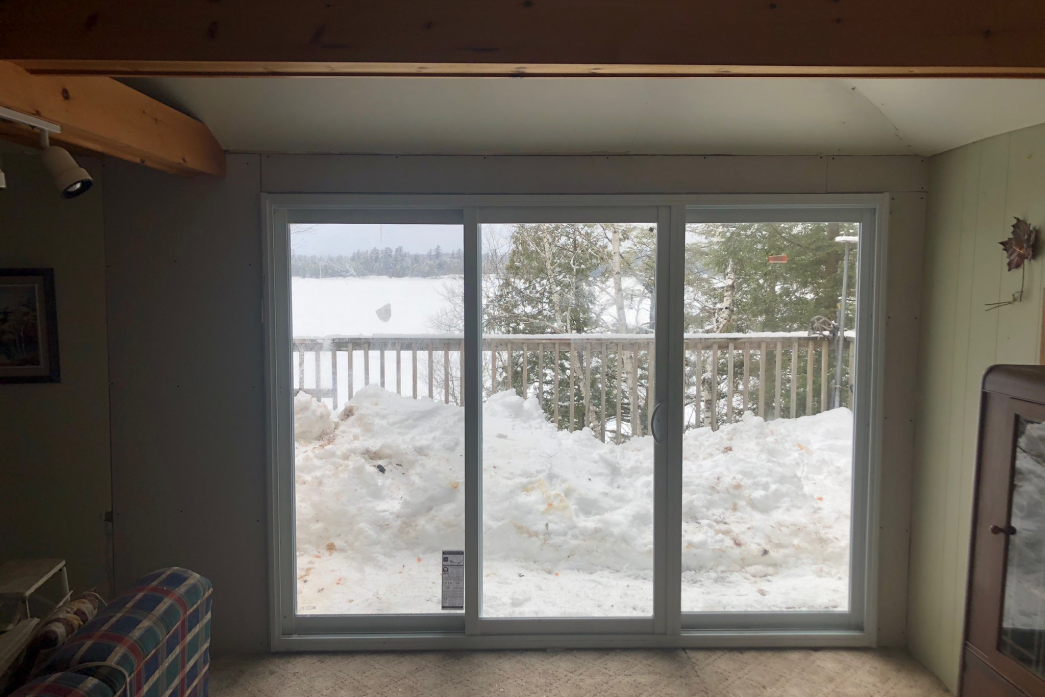 A living room with a sliding glass door leading to a snowy deck.