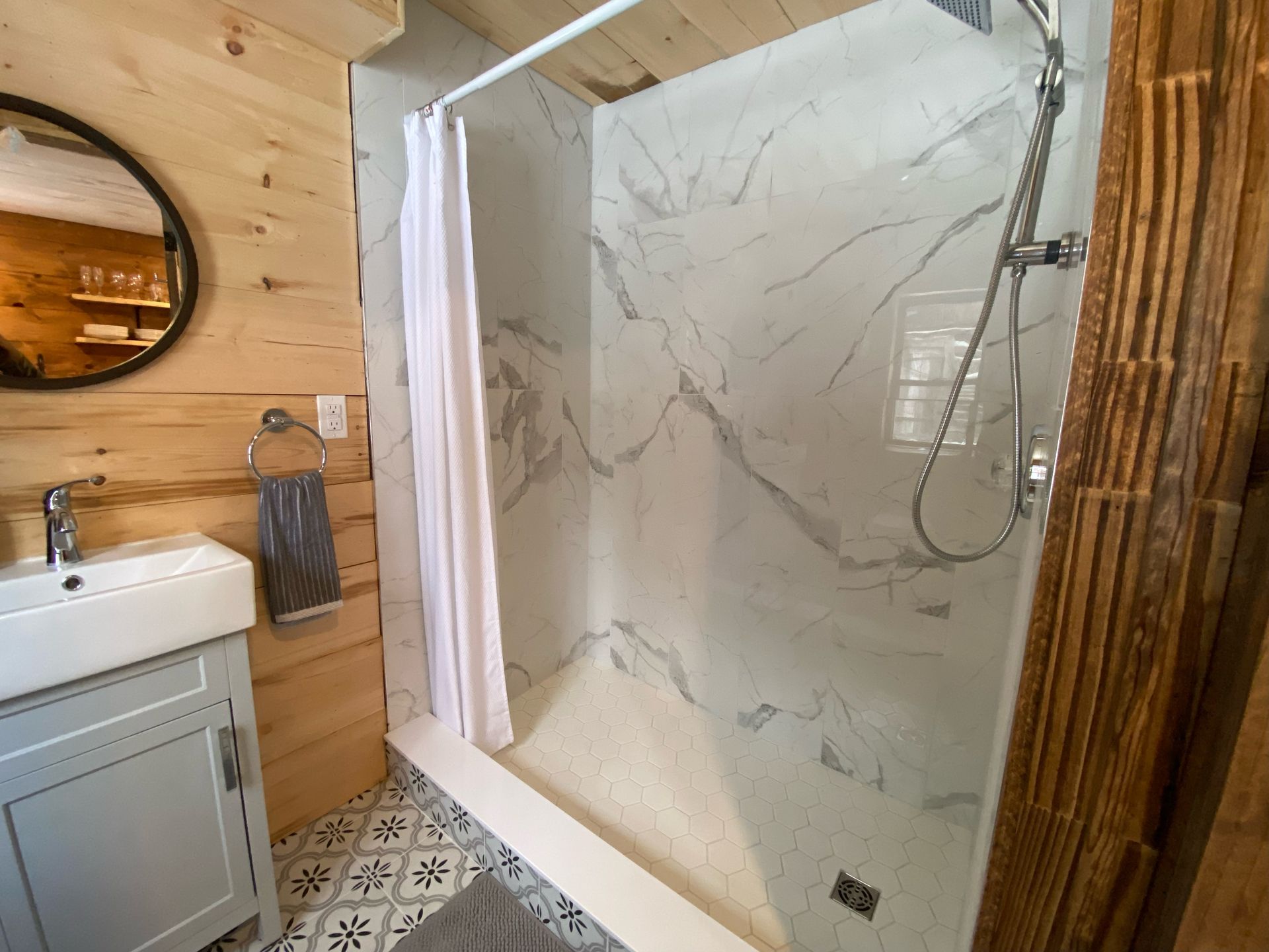 A bathroom with a shower , sink and mirror.