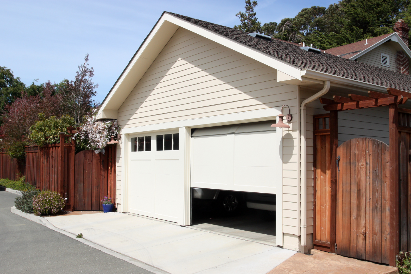 A white garage with a wooden fence in front of it