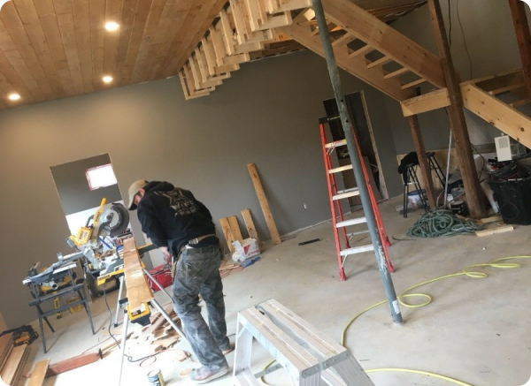 A man is working on a wooden staircase in a room.