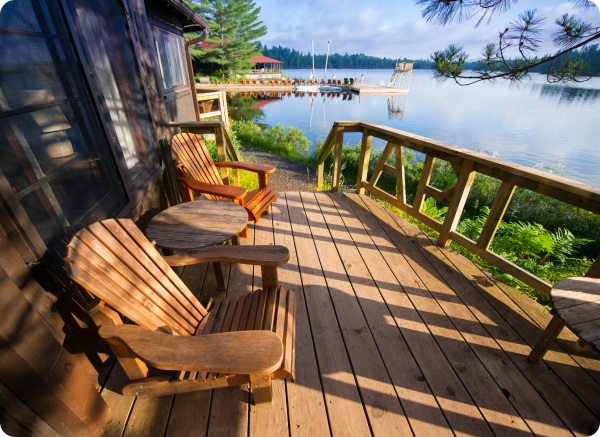 A wooden deck with chairs and a table overlooking a lake